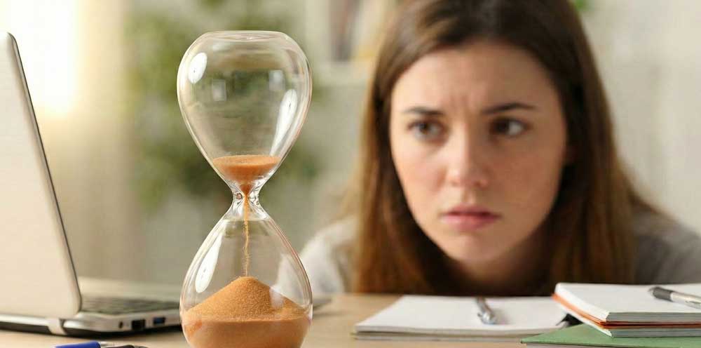Frau blickt angespannt auf eine Sanduhr zur Illustration des Rebound-Phänomens bei ADHS Erwachsene.